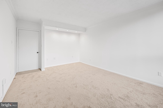 empty room with light carpet, baseboards, and crown molding