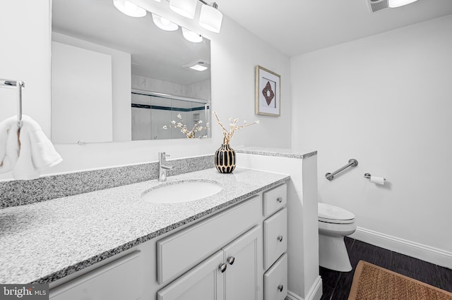 bathroom featuring baseboards, toilet, wood finished floors, vanity, and a shower stall