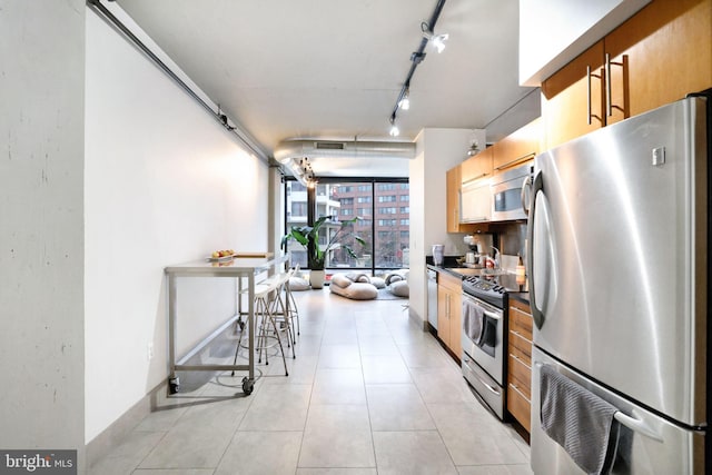 kitchen featuring rail lighting, a breakfast bar area, expansive windows, and stainless steel appliances