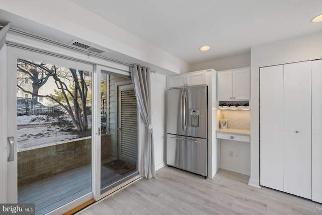 kitchen with white cabinetry, stainless steel fridge, backsplash, and light hardwood / wood-style flooring