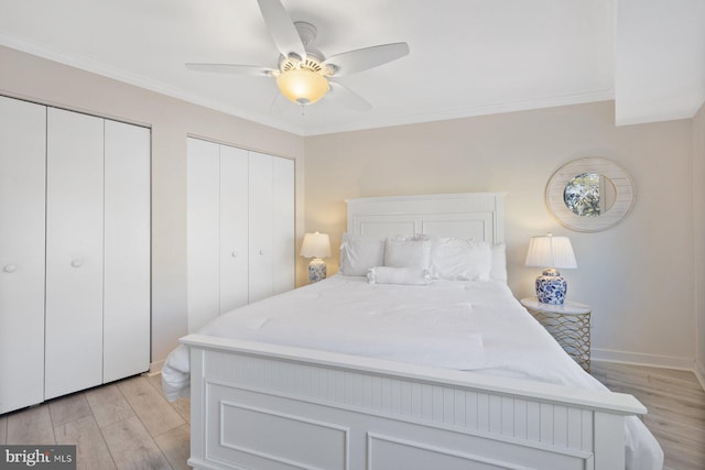 bedroom with multiple closets, ceiling fan, crown molding, and light hardwood / wood-style floors