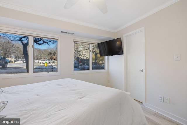 bedroom with light hardwood / wood-style flooring, ornamental molding, and ceiling fan