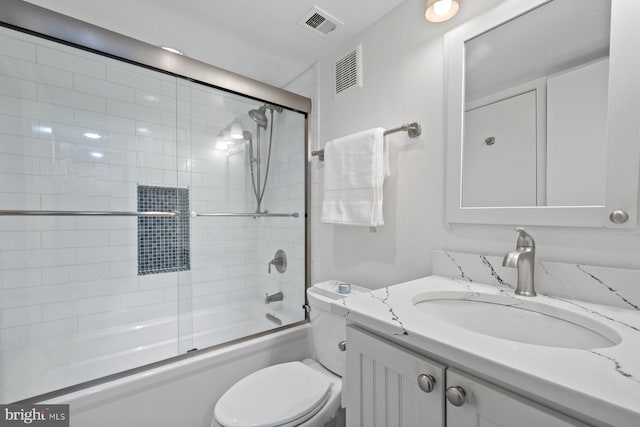 full bathroom with enclosed tub / shower combo, vanity, and toilet