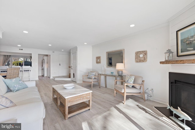 living room featuring ornamental molding, a fireplace, and light hardwood / wood-style flooring