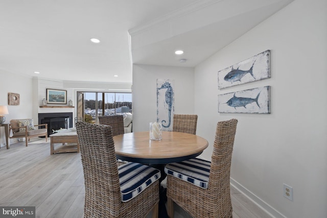 dining area featuring ornamental molding and light hardwood / wood-style flooring