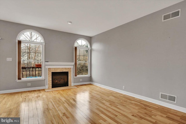 unfurnished living room featuring light wood-type flooring, a fireplace, visible vents, and baseboards