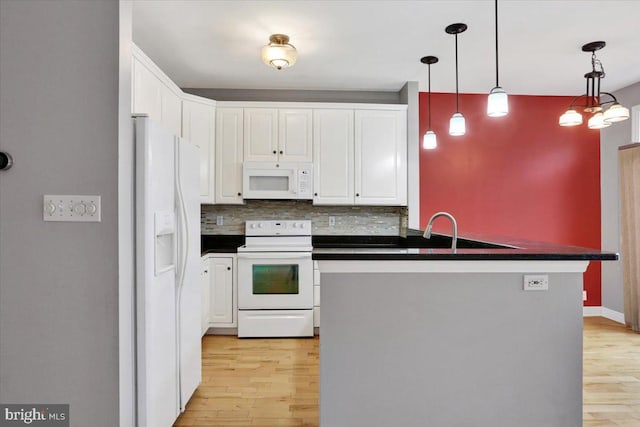 kitchen featuring white appliances, white cabinets, hanging light fixtures, light wood finished floors, and dark countertops