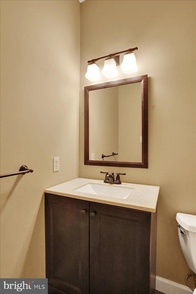 half bath featuring toilet, baseboards, and vanity