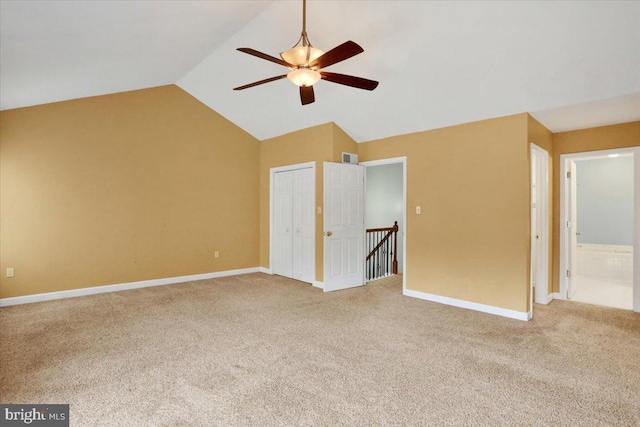 interior space featuring ceiling fan, light colored carpet, baseboards, vaulted ceiling, and a closet