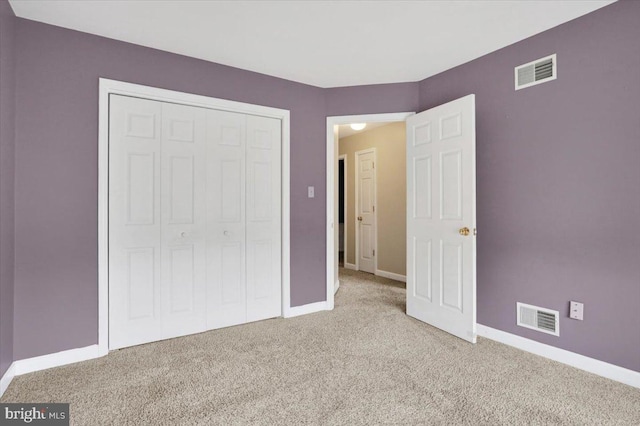 unfurnished bedroom featuring baseboards, visible vents, a closet, and light colored carpet