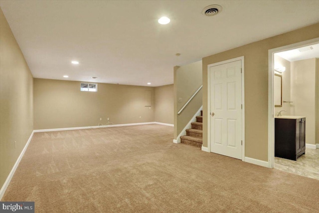 basement with visible vents, light colored carpet, stairway, and baseboards