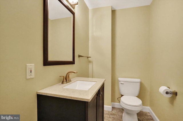 half bathroom with toilet, baseboards, and vanity