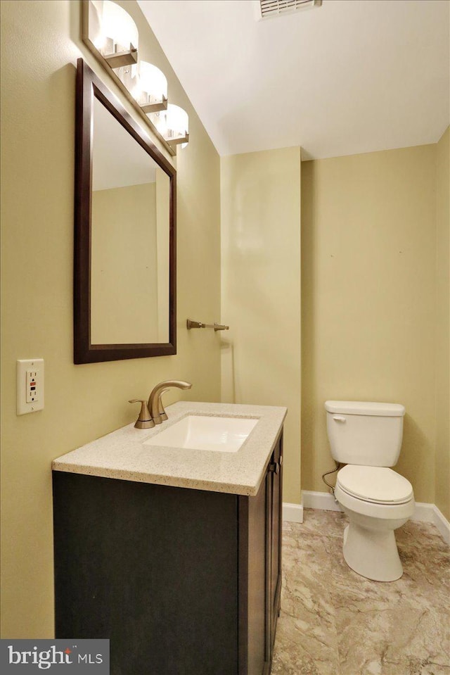 half bathroom featuring toilet, visible vents, baseboards, and vanity