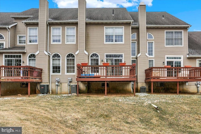 back of property featuring central AC, a chimney, a wooden deck, and a lawn