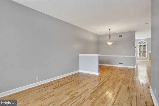 spare room featuring baseboards, visible vents, and light wood-style floors