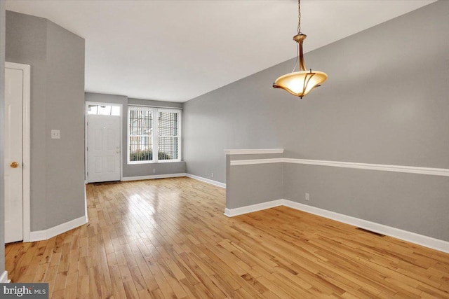 unfurnished room featuring light wood-type flooring, visible vents, and baseboards