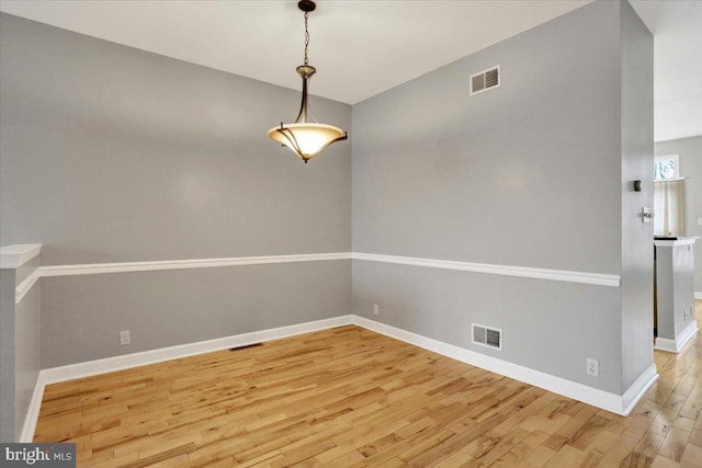 unfurnished dining area with baseboards, visible vents, and wood finished floors