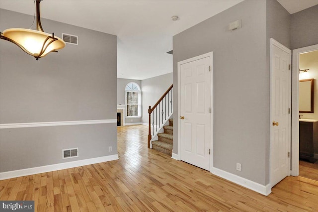 interior space with light wood-style floors, visible vents, baseboards, and stairs