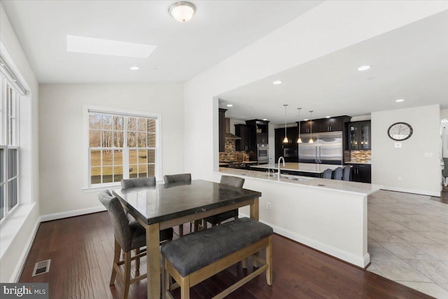 dining room featuring lofted ceiling with skylight, sink, and dark wood-type flooring