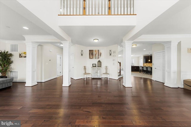 entryway with decorative columns, ornamental molding, dark hardwood / wood-style floors, and a high ceiling