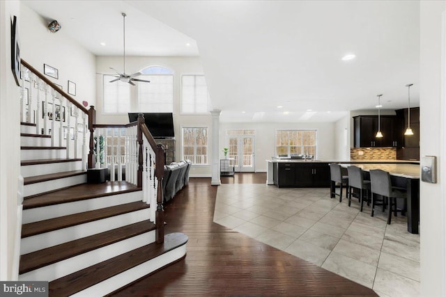 interior space with light tile patterned floors, ceiling fan, and ornate columns