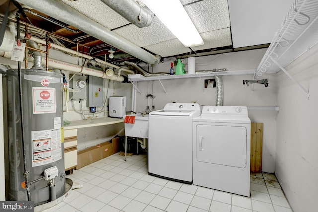 washroom with light tile patterned floors, sink, washing machine and dryer, electric panel, and gas water heater