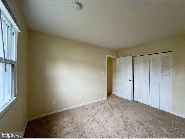 unfurnished bedroom with light colored carpet and a closet