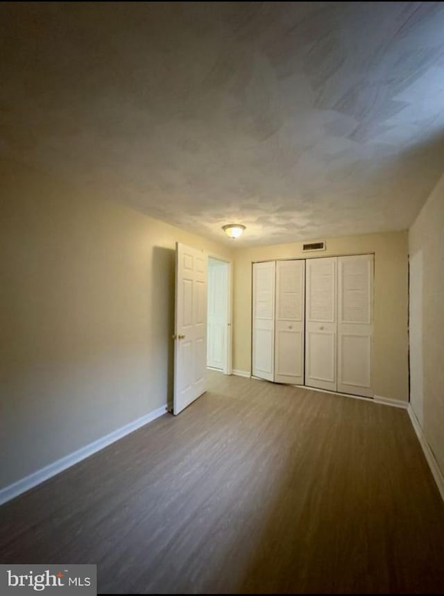 unfurnished bedroom featuring dark wood-type flooring and a closet