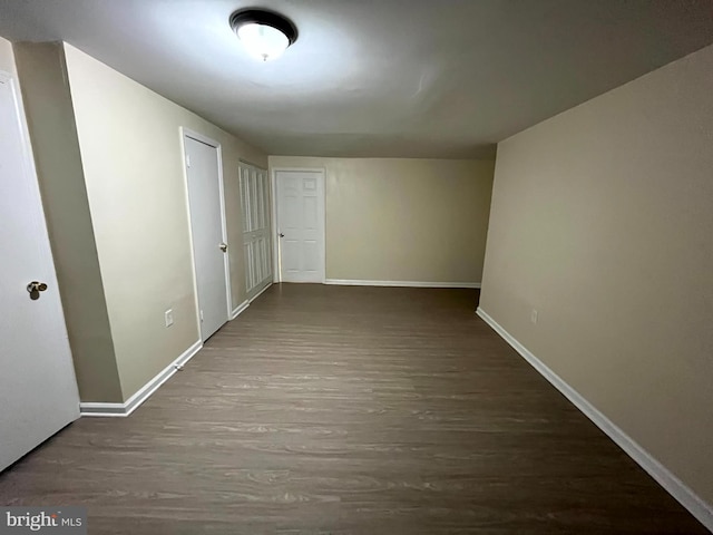 corridor featuring dark wood-type flooring and baseboards