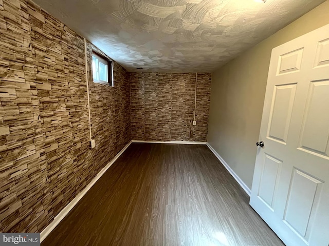 below grade area featuring dark wood-style flooring and baseboards