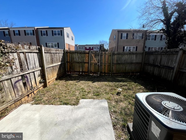 view of yard featuring a fenced backyard, a residential view, central AC, and a patio