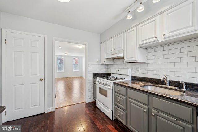 kitchen with tasteful backsplash, sink, white cabinets, dark stone counters, and white range with gas cooktop