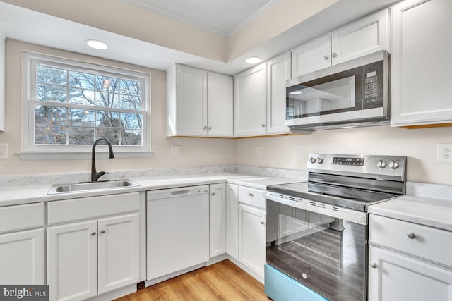 kitchen with white cabinetry, ornamental molding, stainless steel appliances, and sink