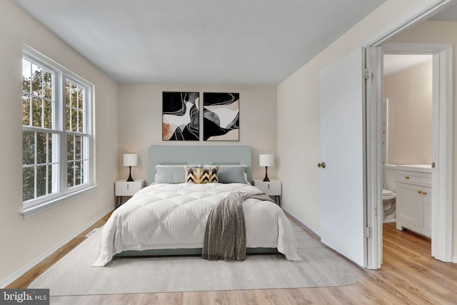 bedroom with light wood-type flooring and ensuite bathroom