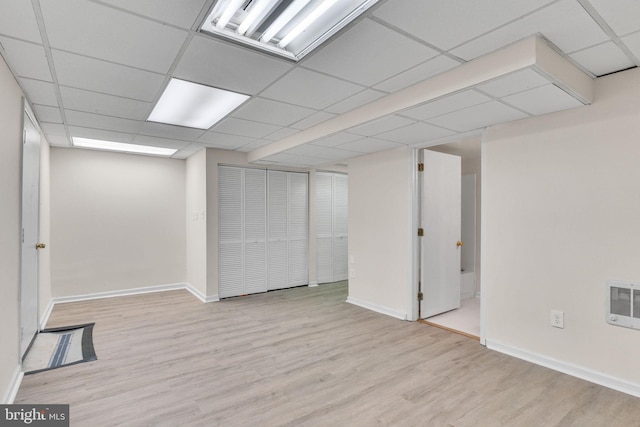 basement featuring heating unit, a paneled ceiling, and light hardwood / wood-style floors