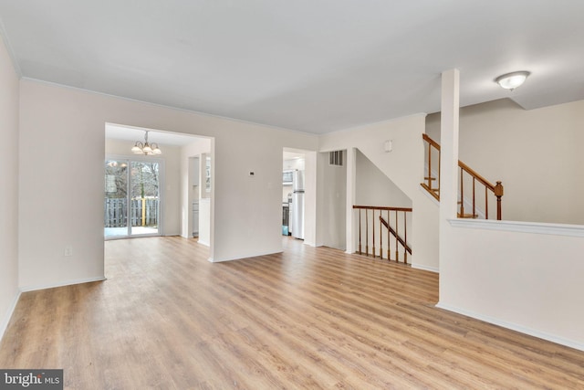 unfurnished room featuring an inviting chandelier and light hardwood / wood-style floors