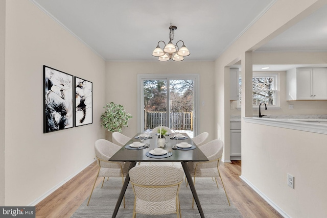 dining room with crown molding, a chandelier, sink, and light wood-type flooring