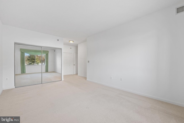 unfurnished bedroom featuring light carpet and a closet