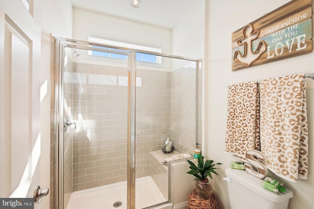 bathroom featuring a shower with shower door and toilet