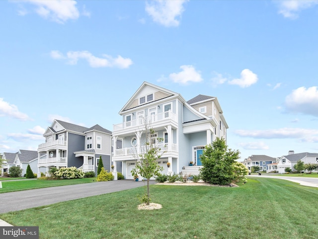 view of front facade featuring a balcony, a garage, and a front lawn