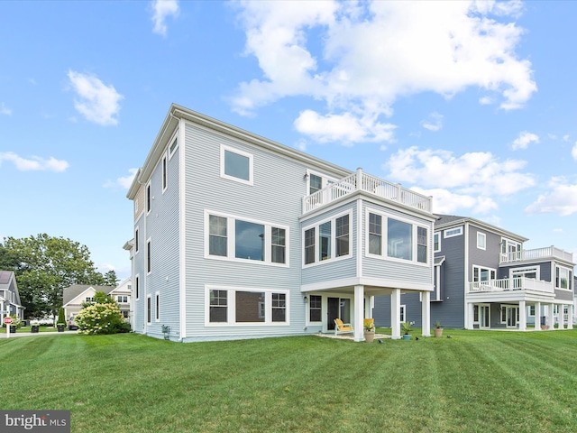 rear view of house featuring a balcony and a yard