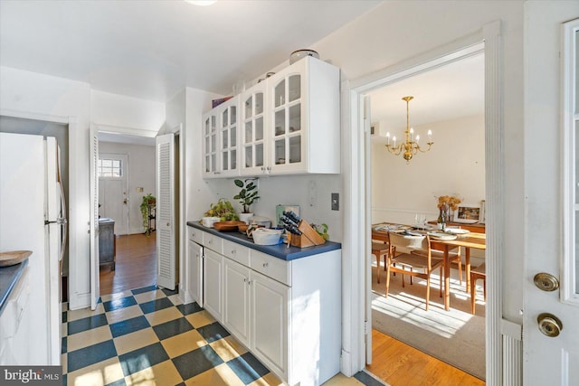 kitchen featuring white refrigerator, dark hardwood / wood-style floors, white cabinets, and an inviting chandelier