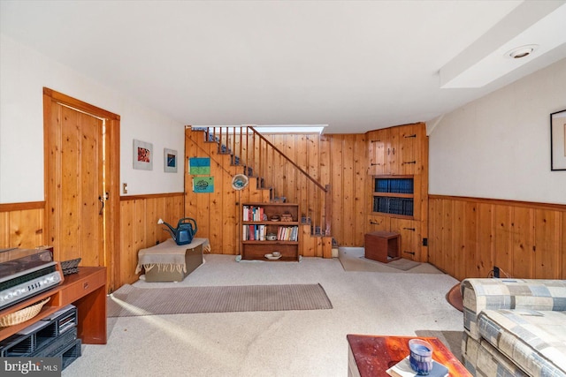 carpeted living room featuring wood walls