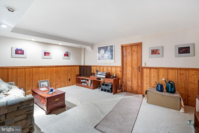 carpeted living room with wood walls