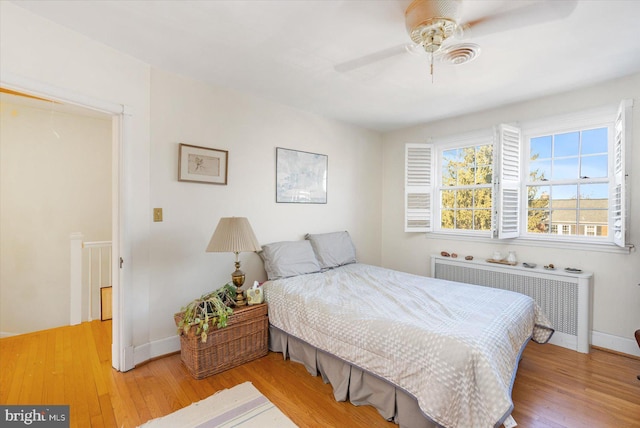 bedroom with ceiling fan, radiator heating unit, and light hardwood / wood-style floors