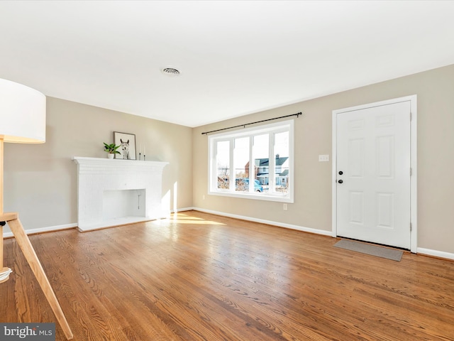 unfurnished living room with a brick fireplace and wood-type flooring