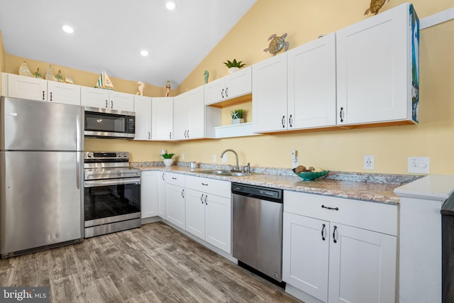 kitchen featuring lofted ceiling, sink, stainless steel appliances, and white cabinets