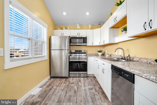 kitchen with lofted ceiling, sink, light hardwood / wood-style flooring, stainless steel appliances, and white cabinets