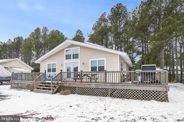 snow covered house featuring a wooden deck