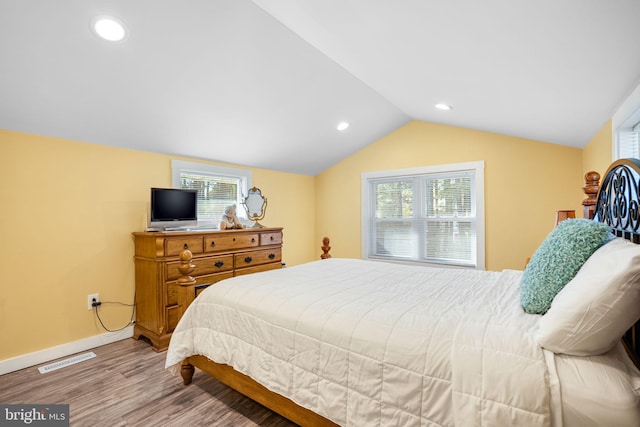 bedroom featuring multiple windows, vaulted ceiling, and light hardwood / wood-style floors